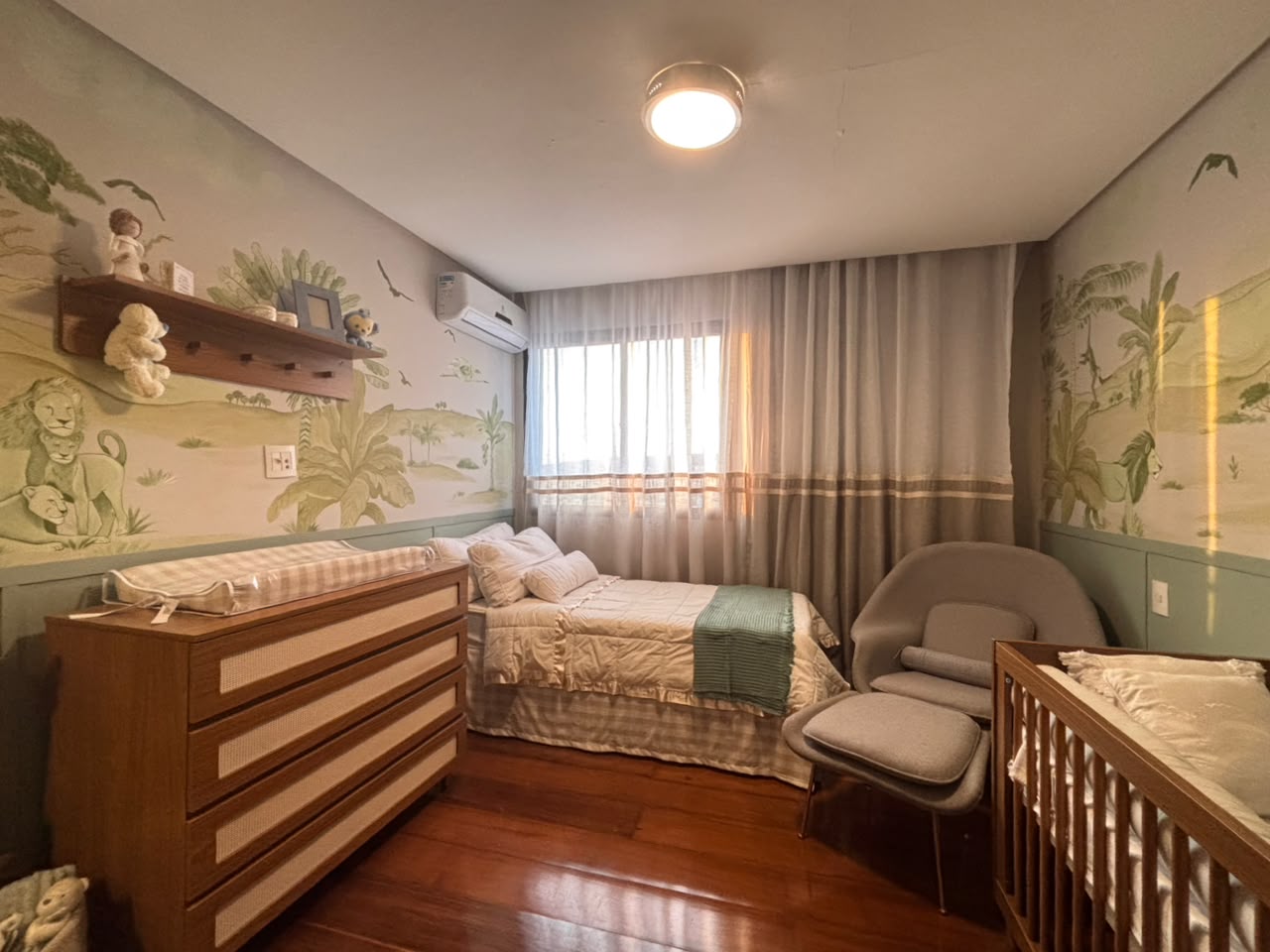 Espaço infantil com papel de parede safari, berço, cama e marcenaria em madeira